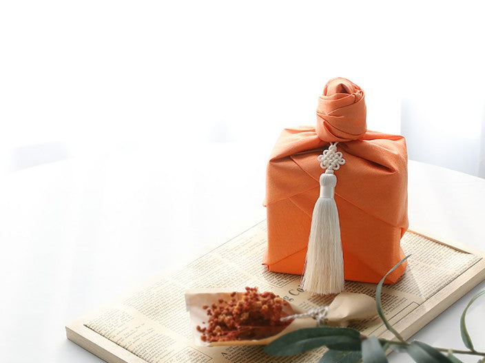bojagi gift wrap — single-layer — Orange — 50 cm — rosette knot on solid ivory background